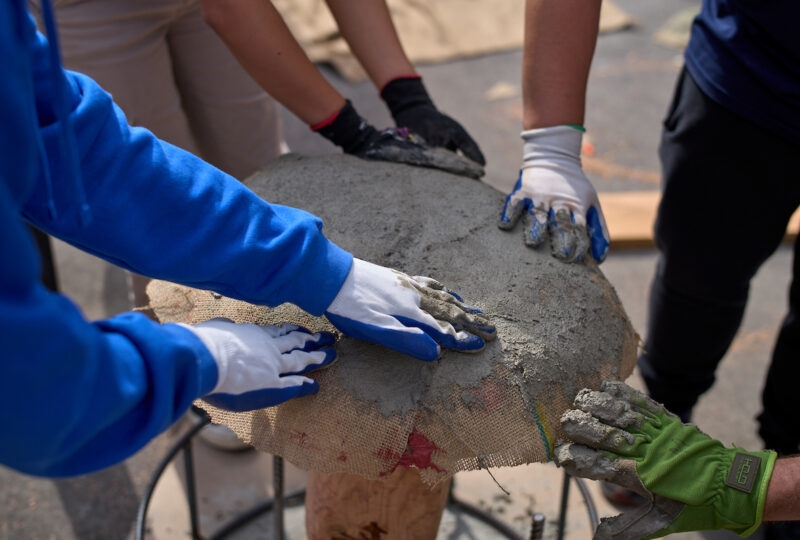 Four students and mentors spreading concrete