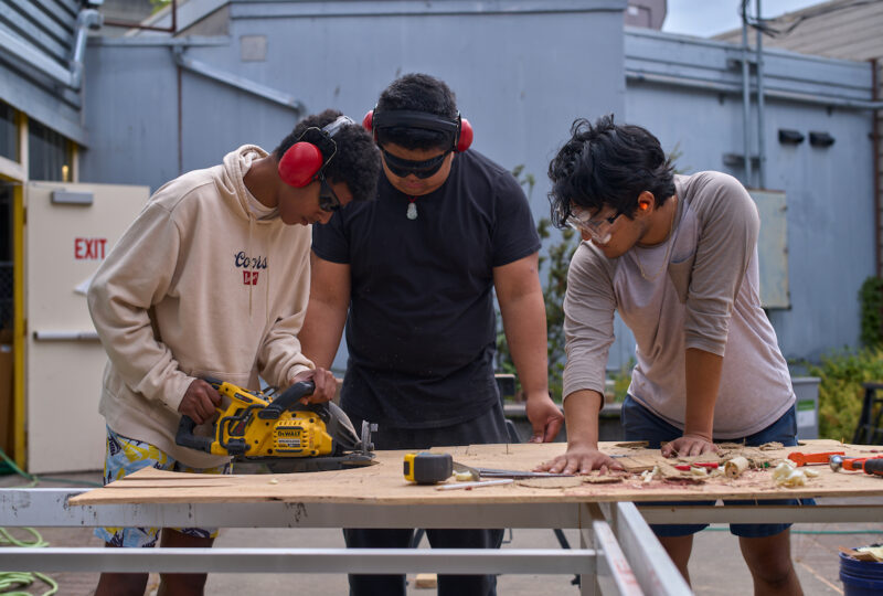 Three students working a circular saw