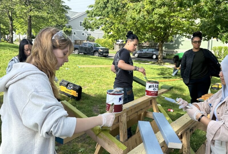 Team painting wood fence boards