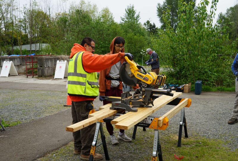 student and mentor using a saw