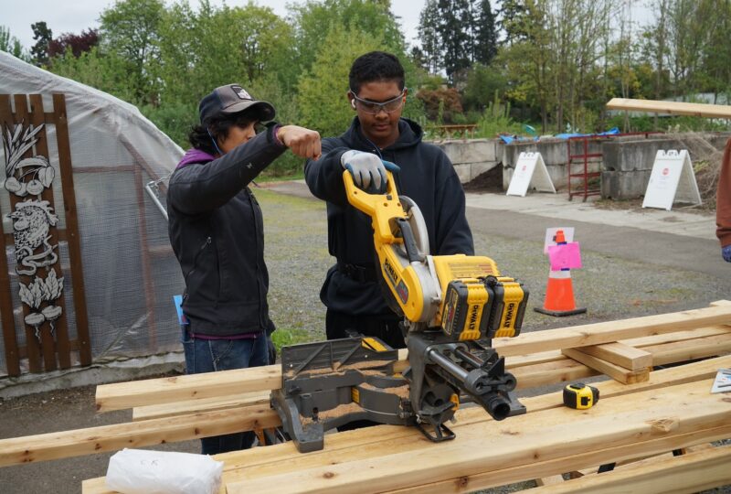 student and mentor using a saw